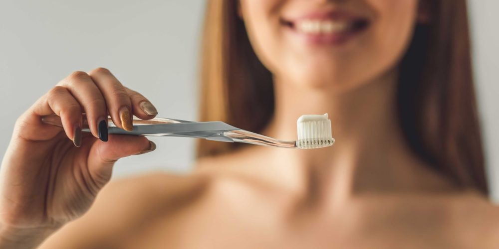 Chica sonriendo sosteniendo un cepillo de dientes con pasta de dientes