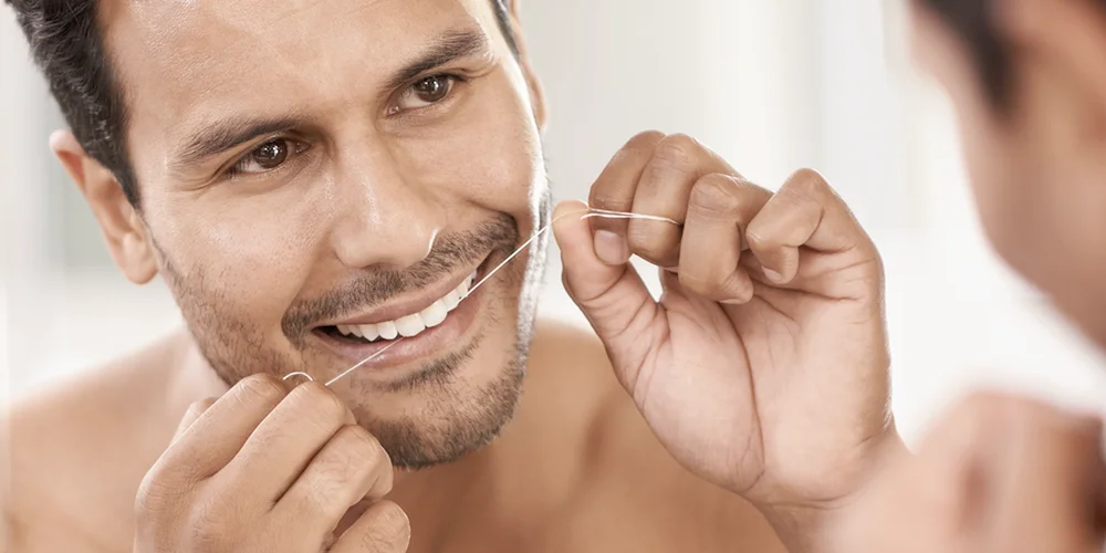 Hombre usando el hilo dental - Clínica Dental Soria - Salamanca
