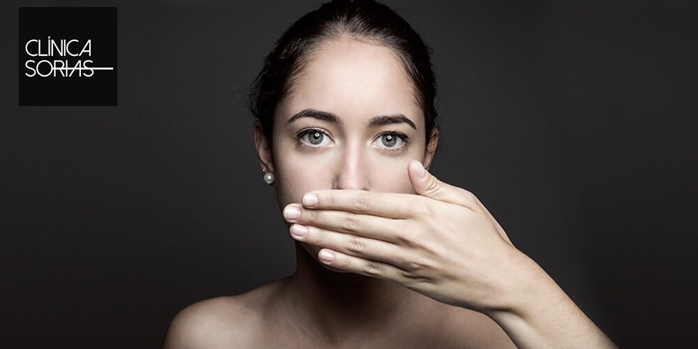 Chica tapándose la boca por el mal aliento.