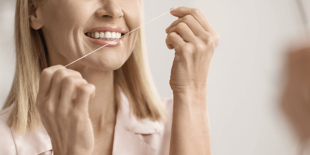 Mujer hilo dental - Cuidado de encias - Clínica Deltal Soria - Salamanca