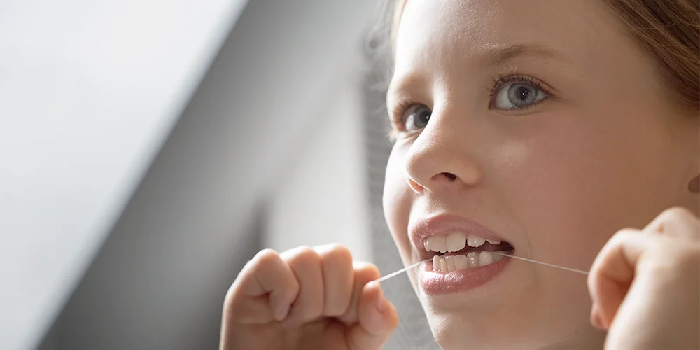 Niña usando el hilo dental - Clínica Dental Soria - Salamanca