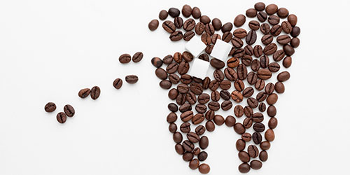 Granos de café formando un diente, con un terrón de azucar