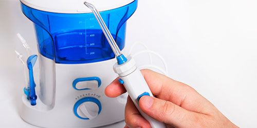 Mano sujetando el cepillo de un irrigador bucal