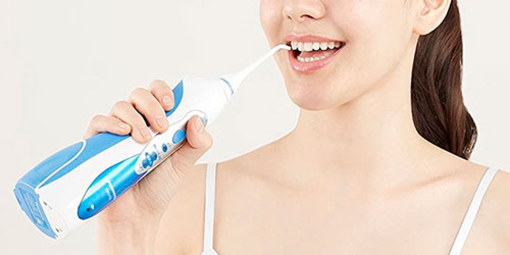 Chica usando un irrigador bucal