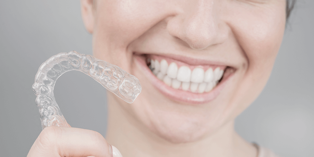 Mujer sujetando feliz su retenedor dental